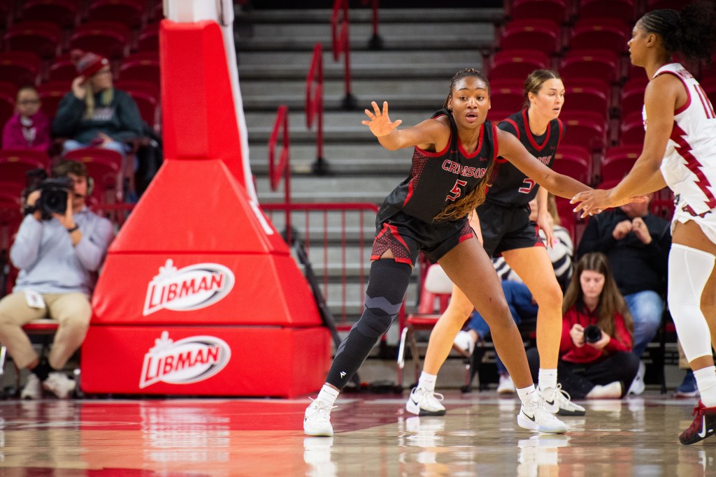 Harvard guard Gabby Anderson is shown in a defensive stance. Her player doesn't have the ball, so she's watching the action elsewhere on the court out of the corner of her eye.