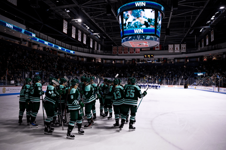 The Fleet celebrate their win with team fist bumps and hugs. They are all wearing green home uniforms.
