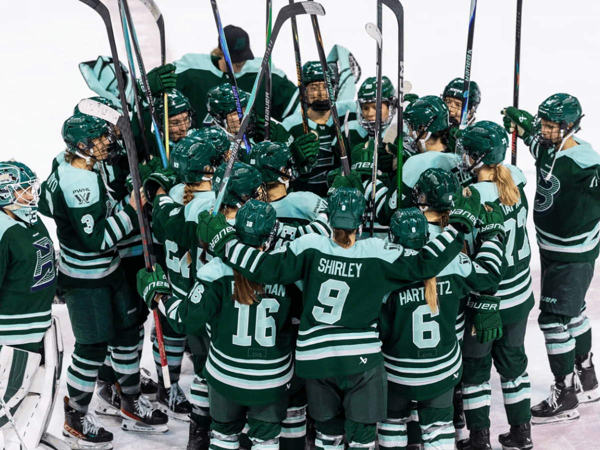 The Fleet celebrate their win with a tight group hug at center ice. They are all wearing green home uniforms.