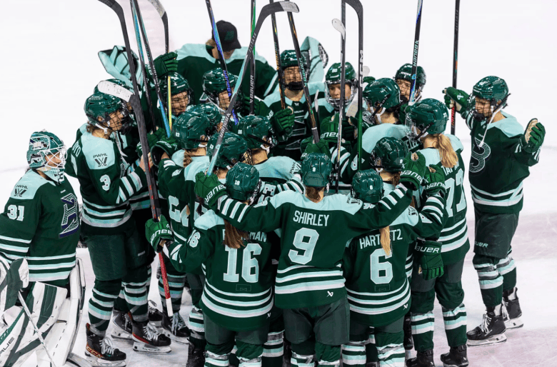 The Fleet celebrate their win with a tight group hug at center ice. They are all wearing green home uniforms.