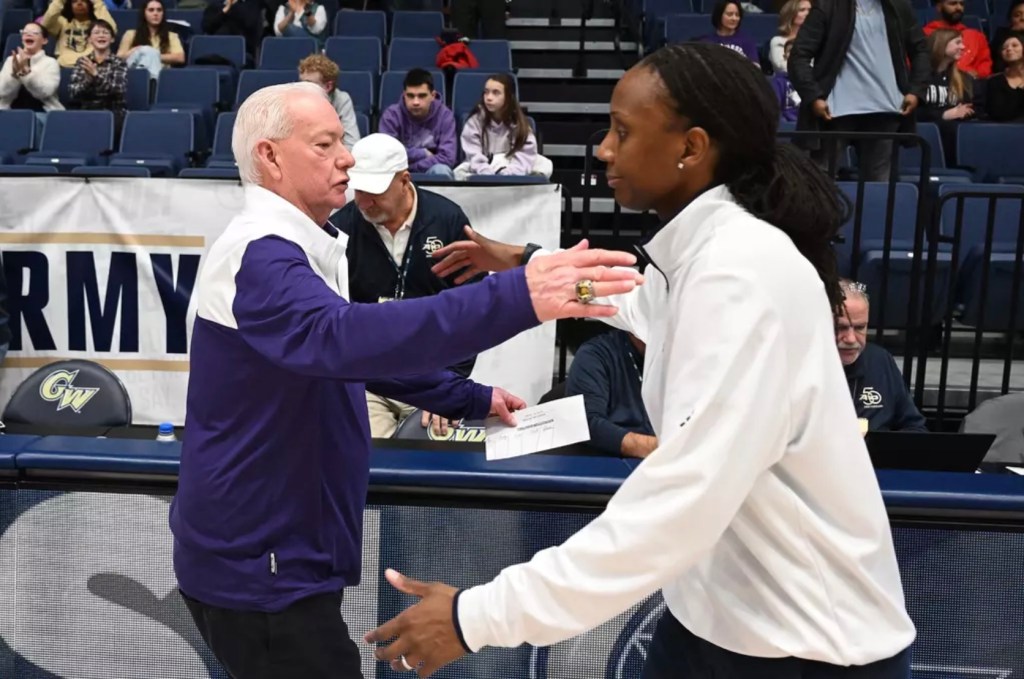 Northwestern head coach Joe McKeown and George Washington head coach Ganiyat Adeduntan are each shown from the side, reaching their arms out to hug one another.