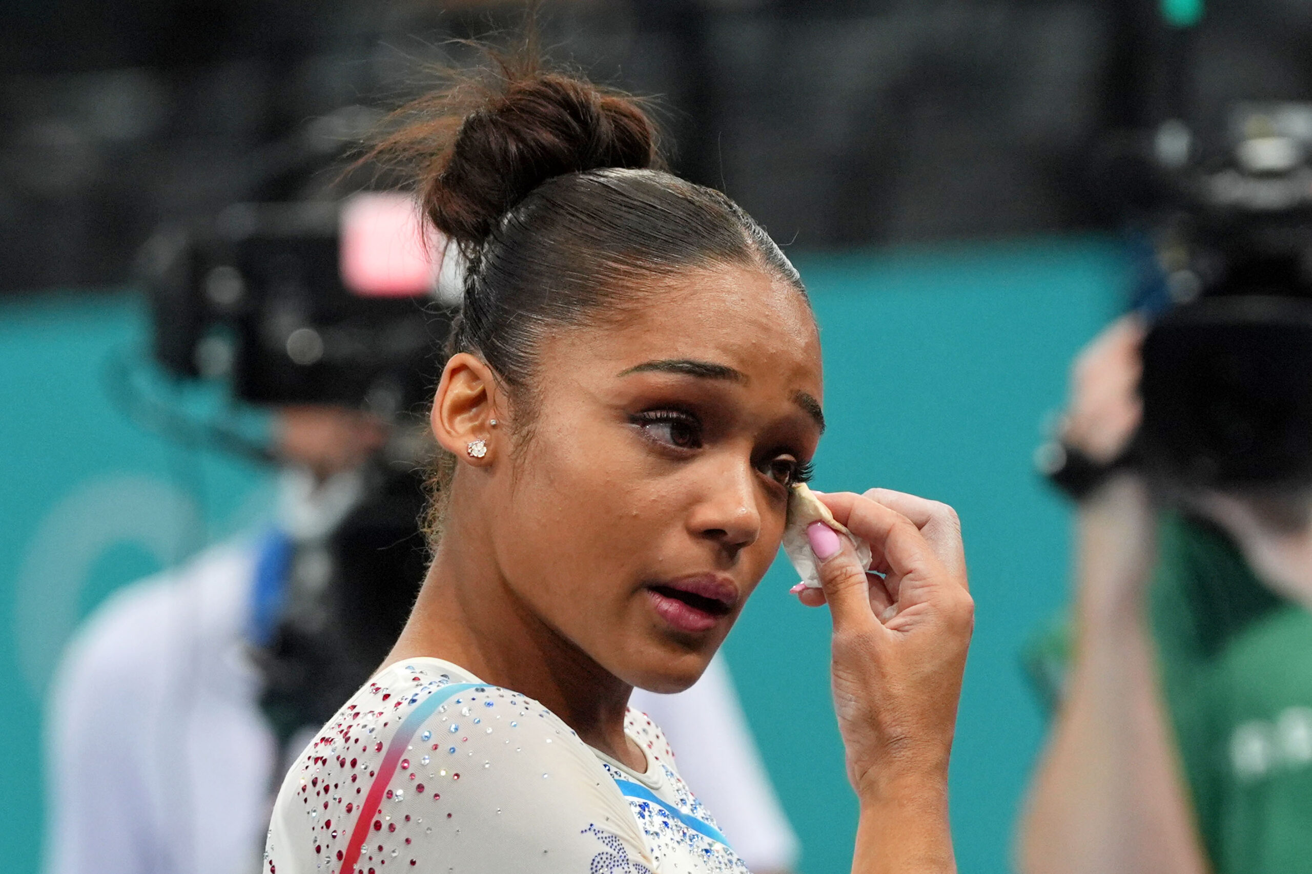 Melanie de Jesus dos Santos of France, dressed in a white leotard, wipes away tears after the French team did not qualify to the Olympic team final.