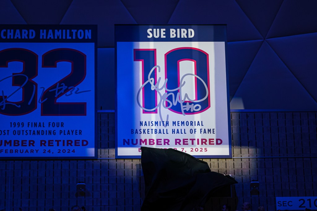 A spotlight shines on a banner that says "Sue Bird" with the number 10