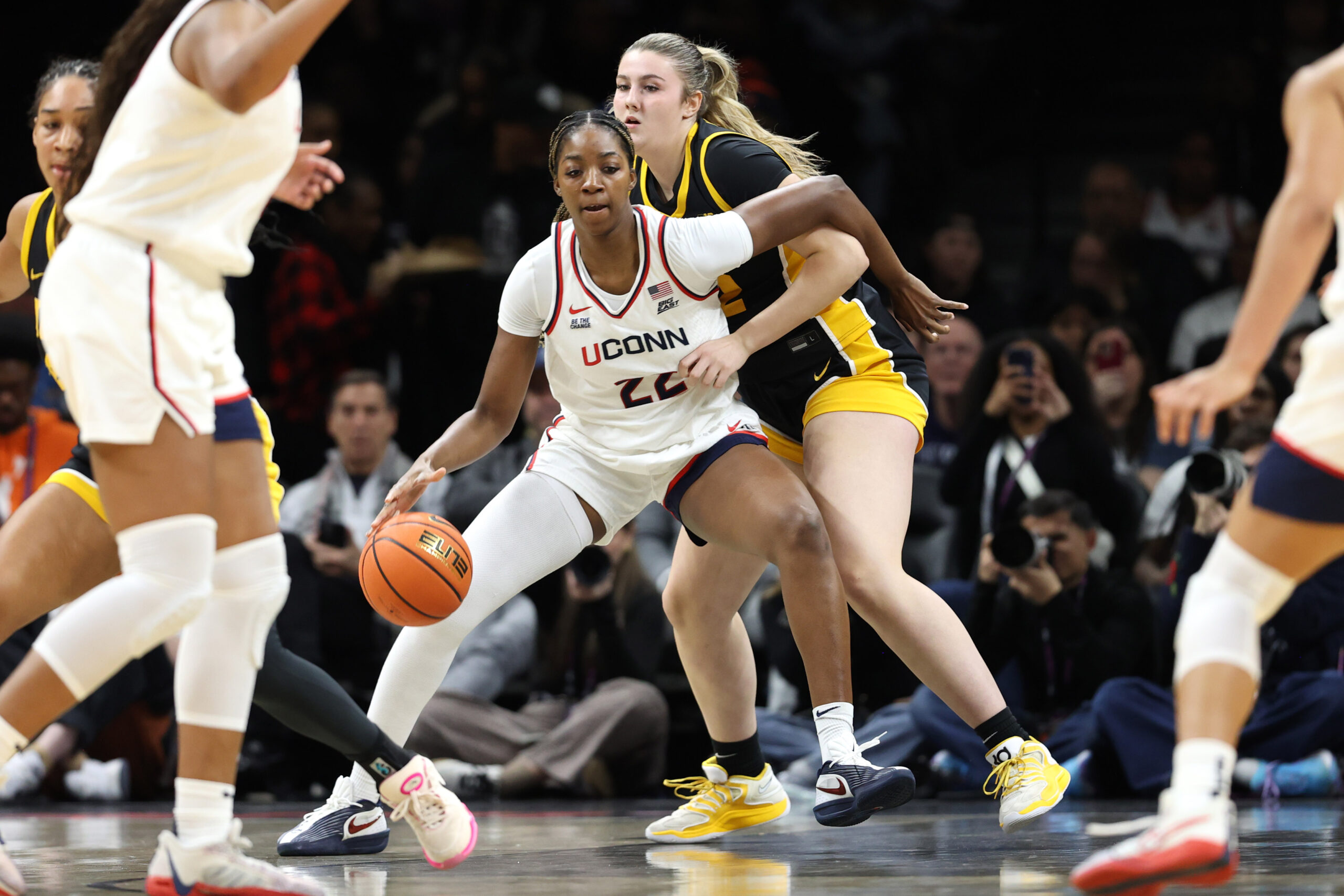 UConn Huskies forward Serah Williams drives to the basket, handling the ball with her right hand and navigating around an Iowa defender with her left arm.