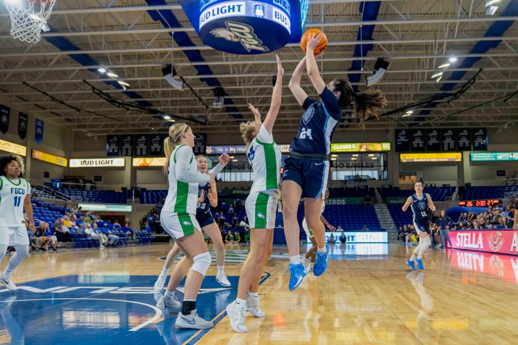 Columbia guard Riley Weiss twists in midair to square her shoulders as she shoots a short-range jump shot near the baseline and over an FGCU defender.