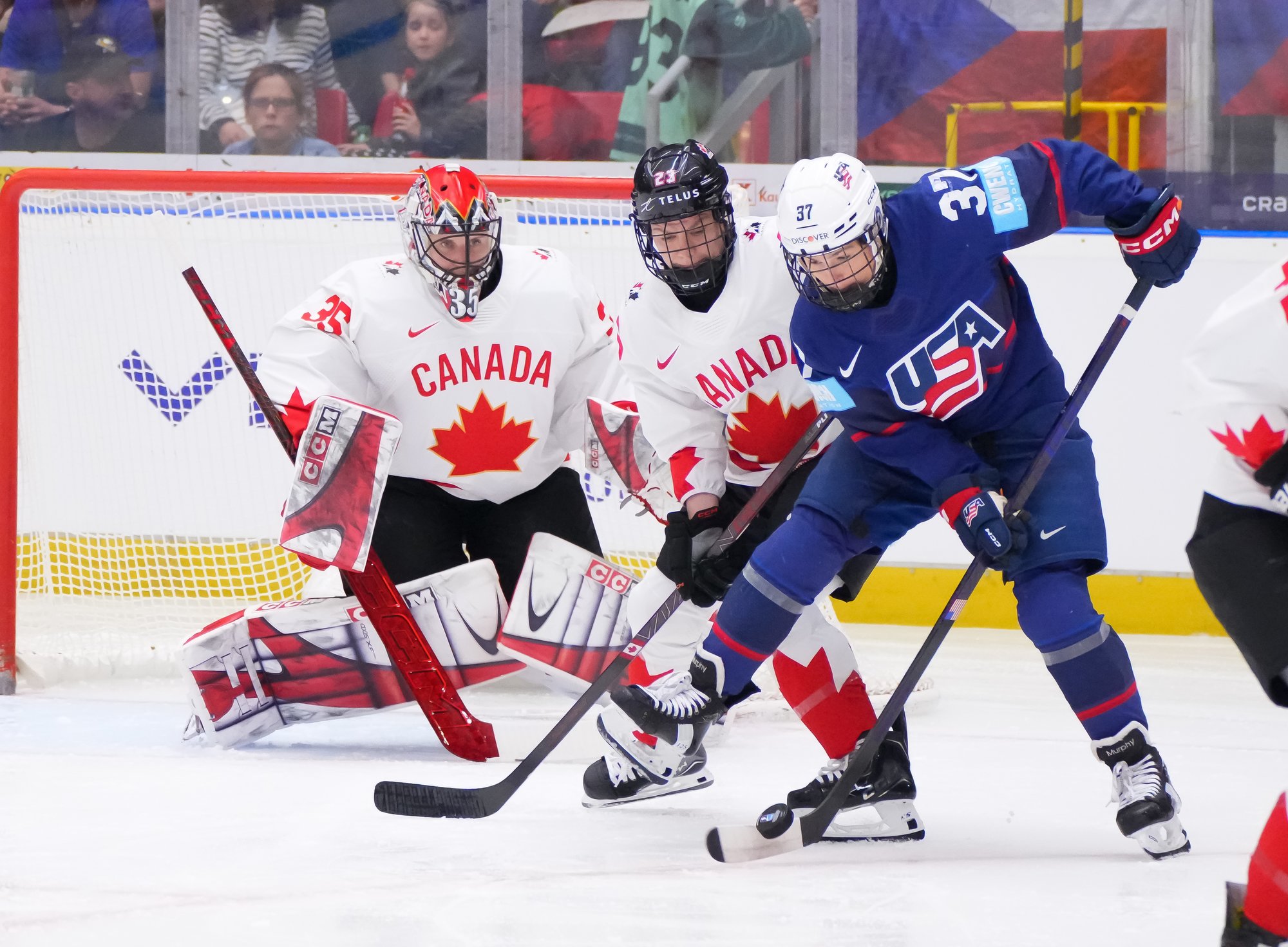 American and Canadian hockey players fight for the puck in front of a Canadian defender