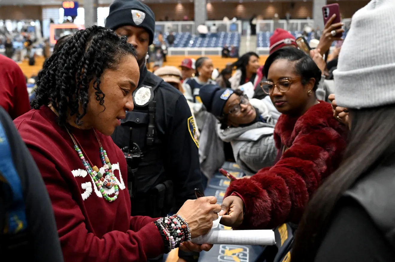 South Carolina head coach Dawn Staley signs a small slip of paper for a fan on her way to the locker room.
