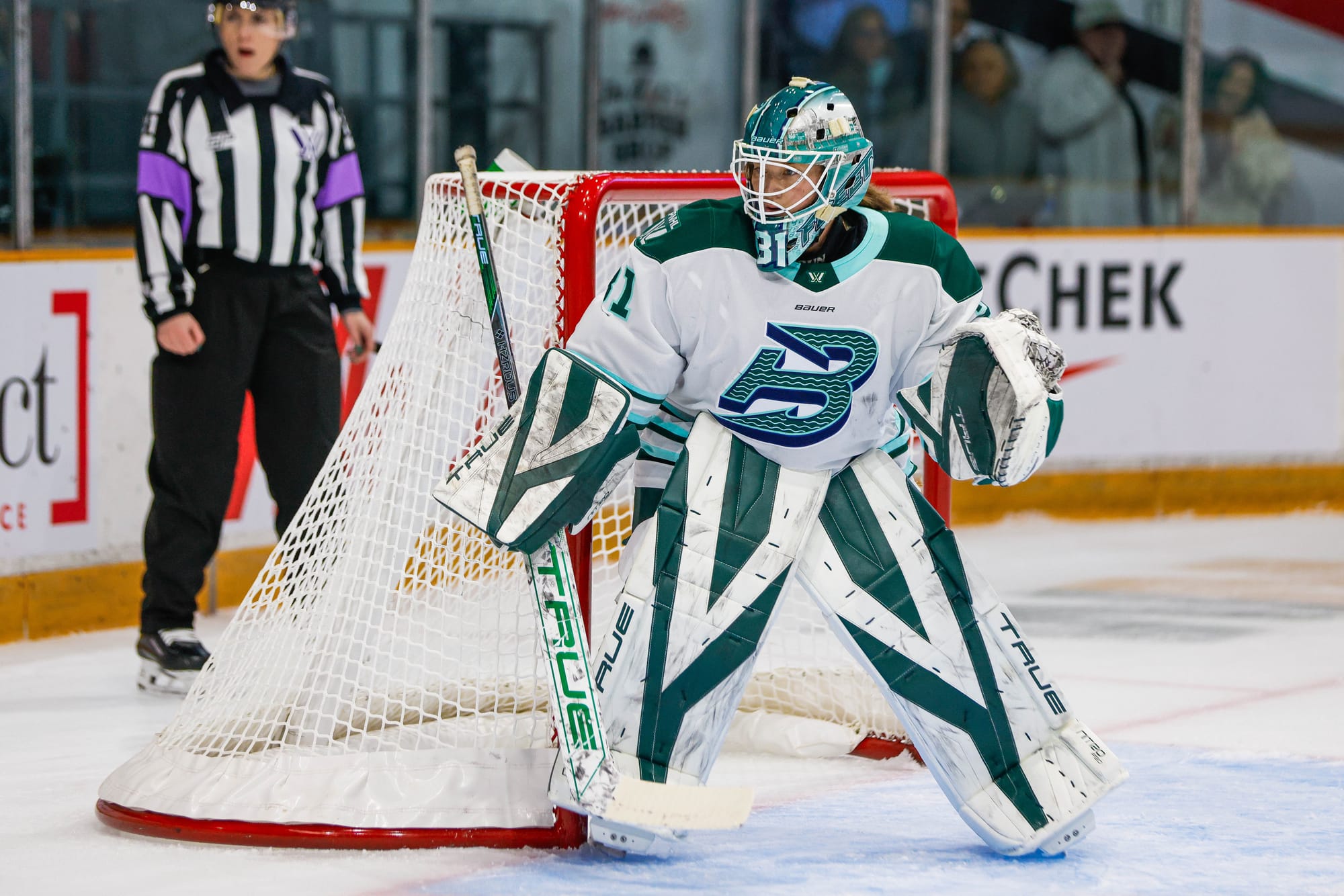 Frankel stands watching a play unfold out of frame in the corner. She is wearing a white away uniform.