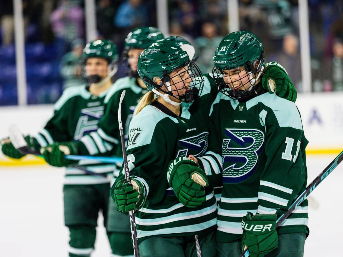 Hartmetz and Müller smile and hug as they celebrate a win. They are both wearing green home uniforms.