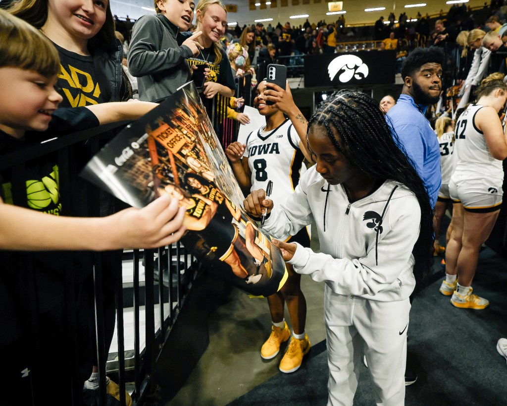 Iowa guard Chazadi “Chit-Chat” Wright (11) signs autographs for excited young fans at Carver-Hawkeye Arena in Iowa City, Iowa.