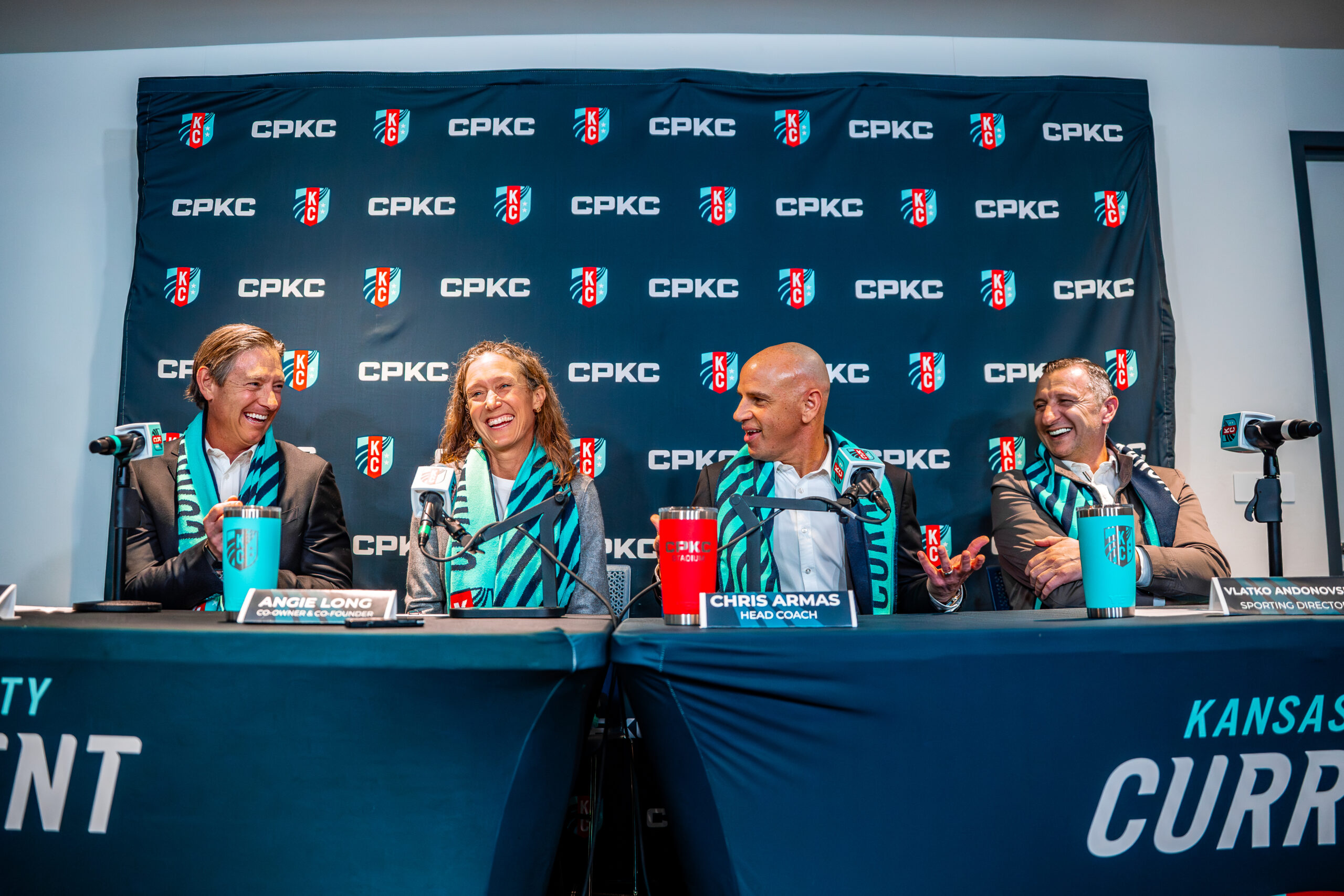 Chris Long, Angie Long, Chris Armas and Vlatko Andonovski sit at a table in front of a KC Current-branded backdrop.