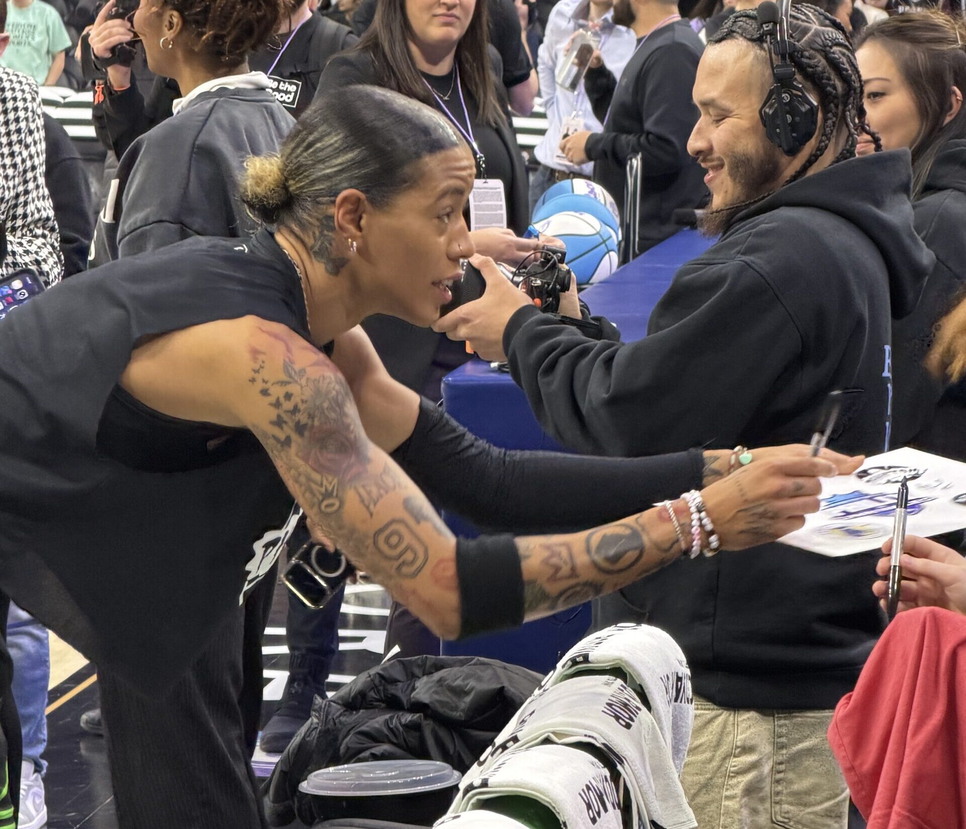Natasha Cloud hands a pen and piece of paper back to a fan after signing an autograph before an Unrivaled game in Philadelphia.