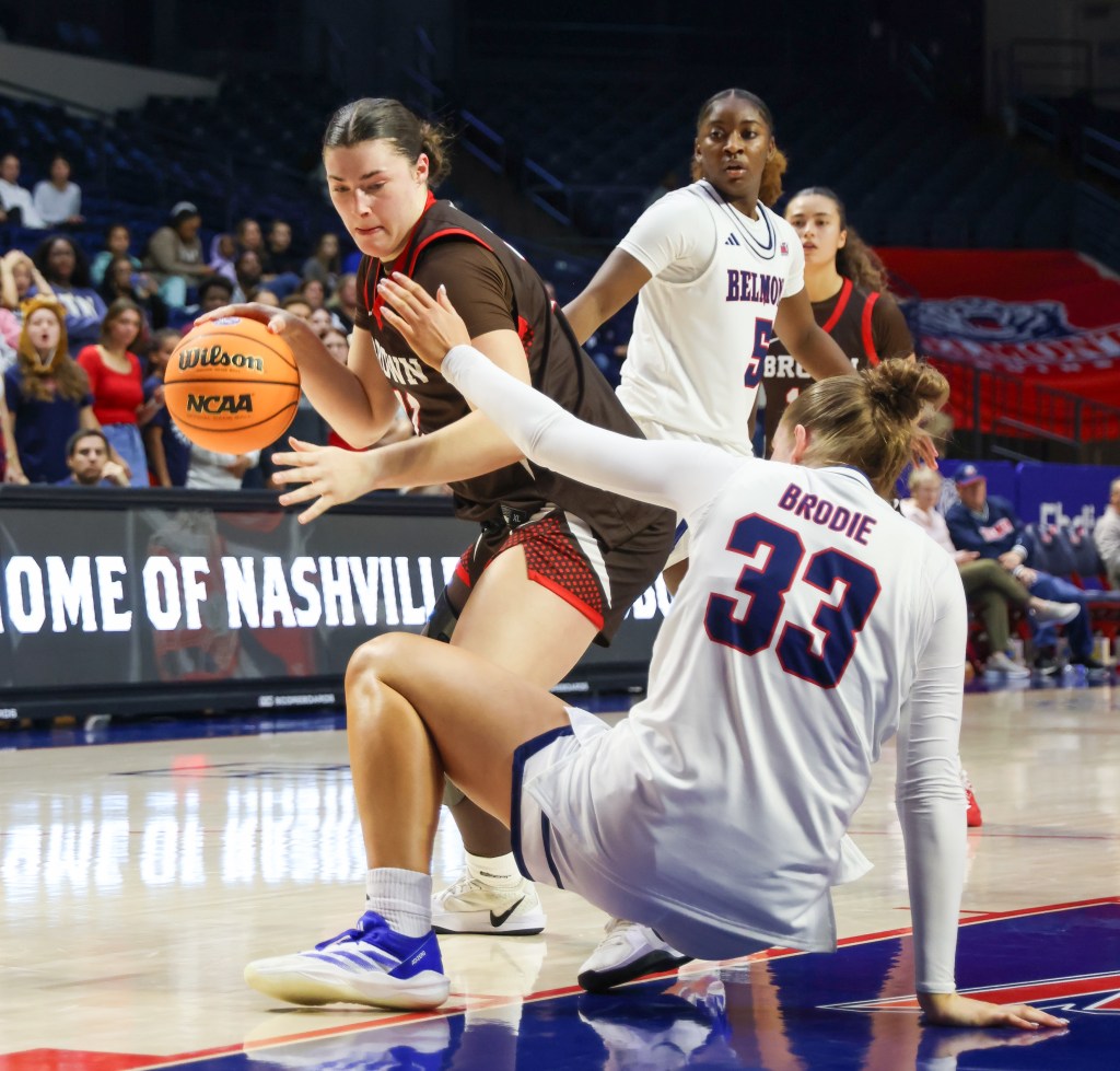 Brown forward Alyssa Moreland dribbles the ball with her right hand near the block. A Belmont defender in front of her scrambles to get up from the floor and cut off Moreland's drive.