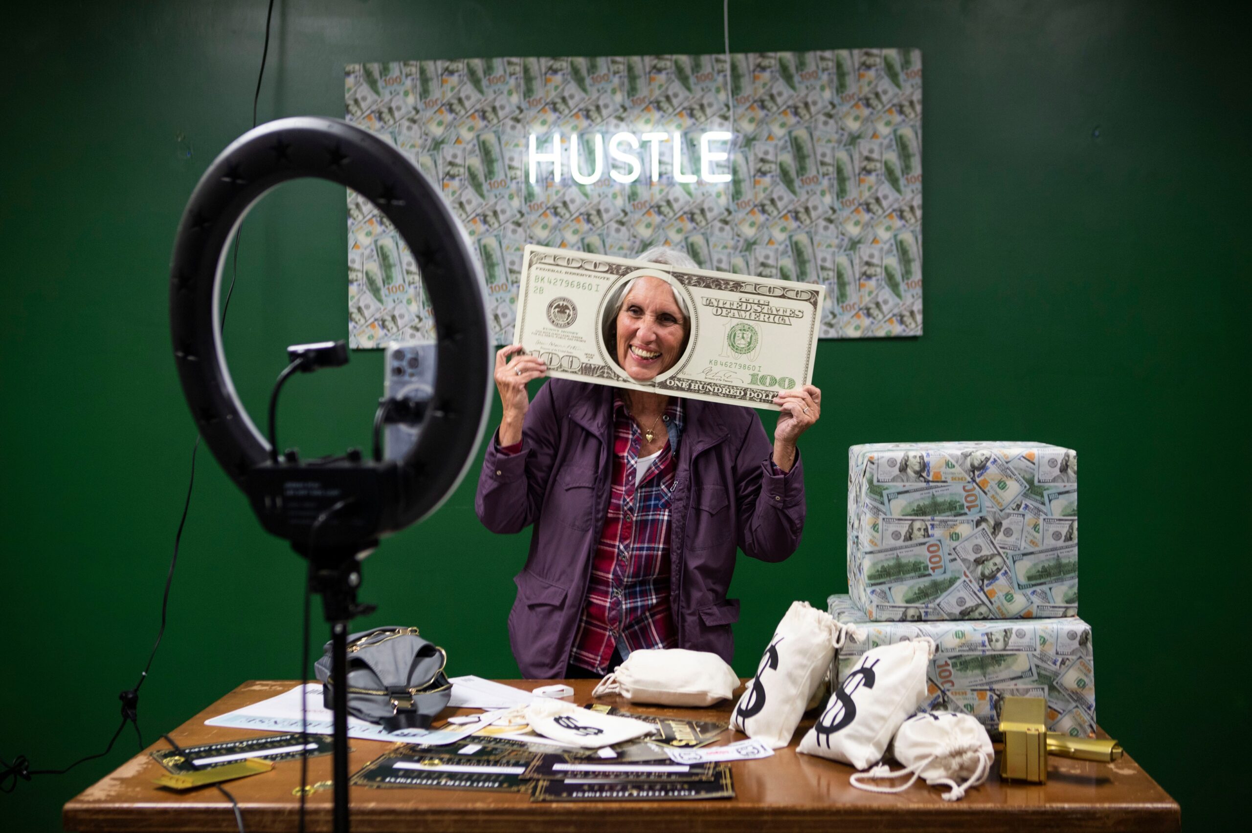 A lady looks through a comically large piece of money.