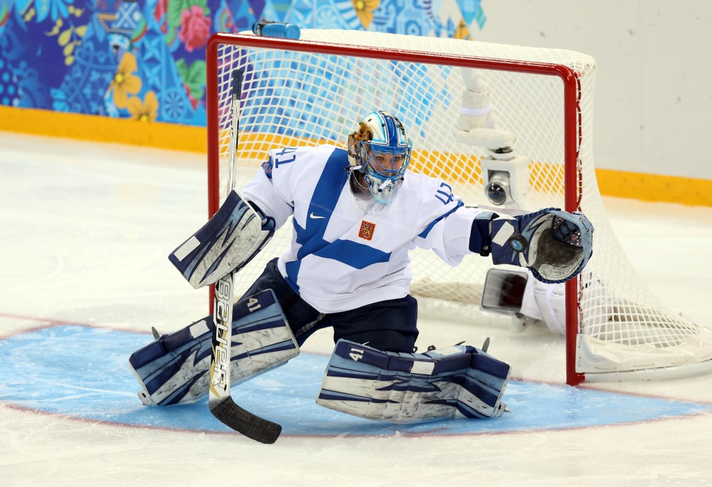 Finland goalkeeper Noora Raty (41) makes a save, reaching her left hand out to block the puck.