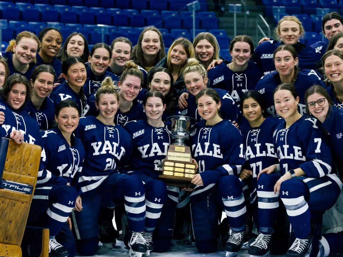 Yale's women's hockey team posing with their ECAC regular-season championship trophy.