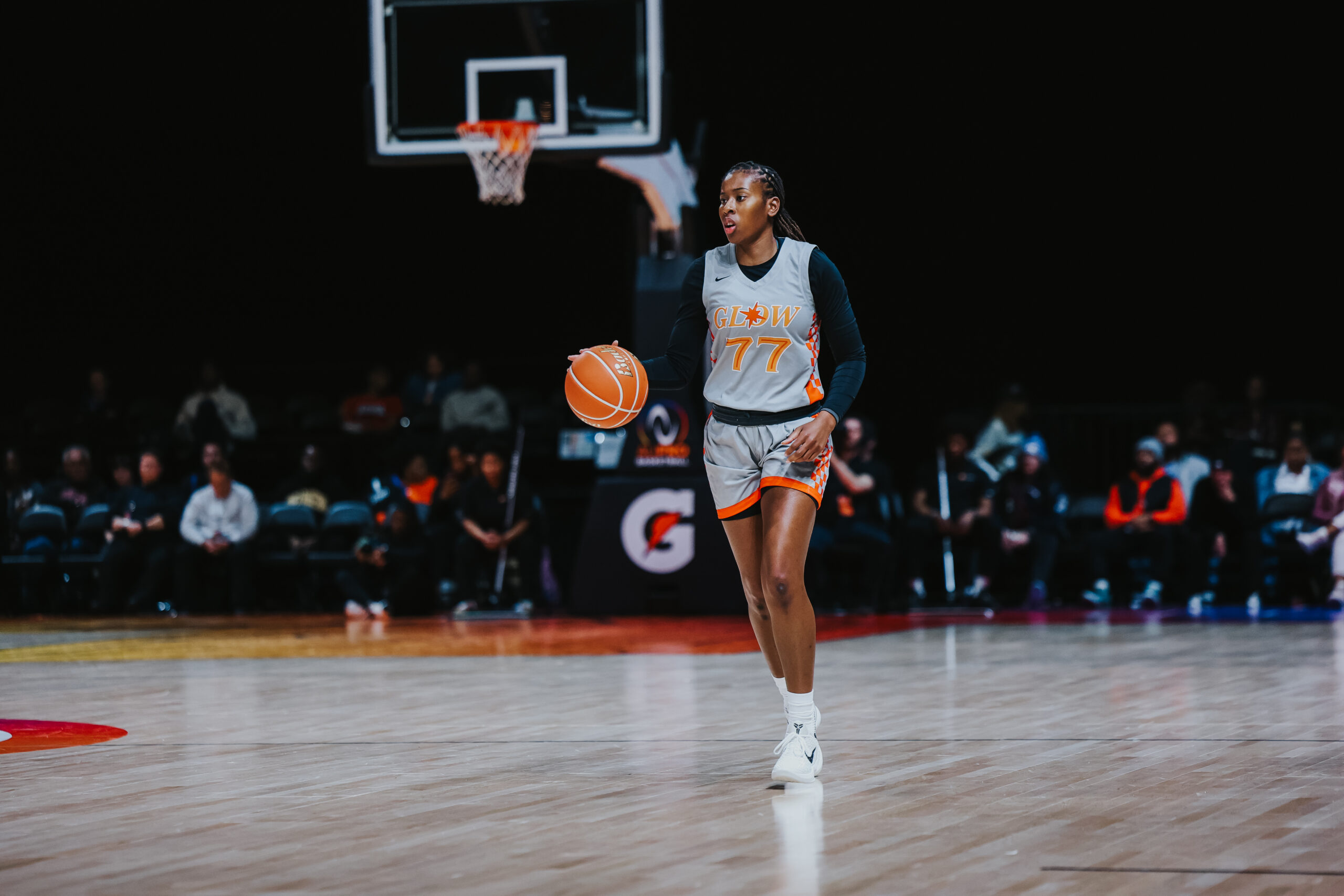 A player in a Glow uniform dribbles the ball down a basketball court