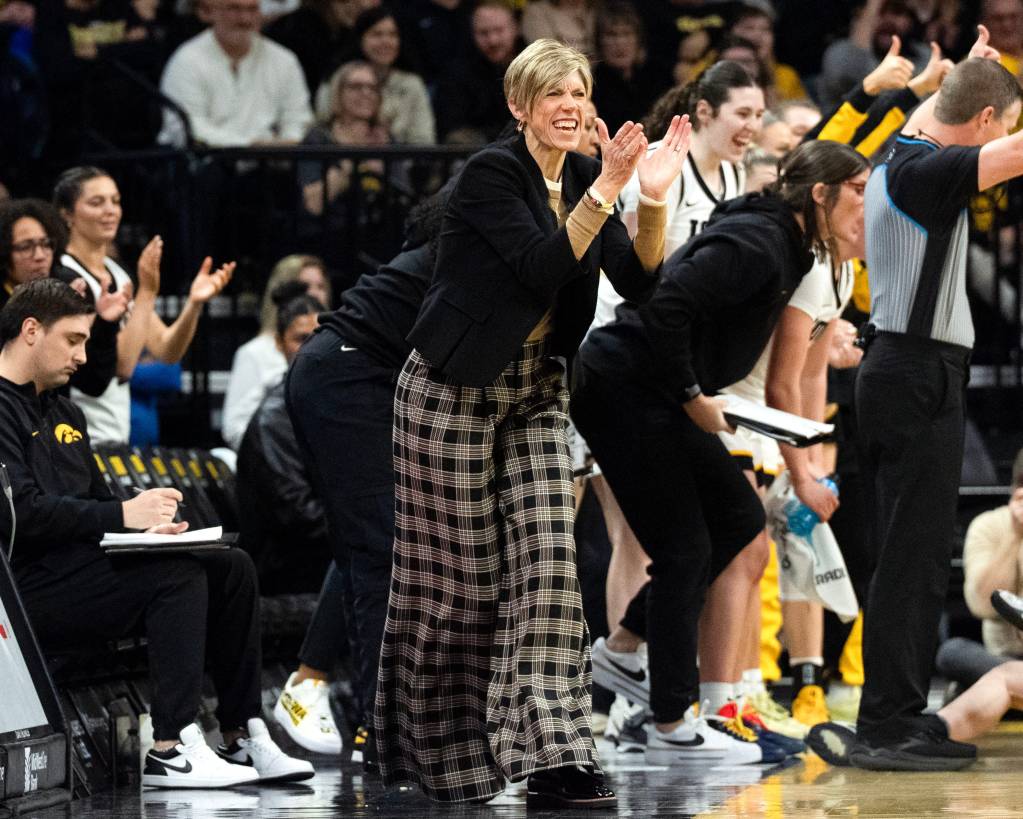 Jan Jensen smiles and claps on the sideline.