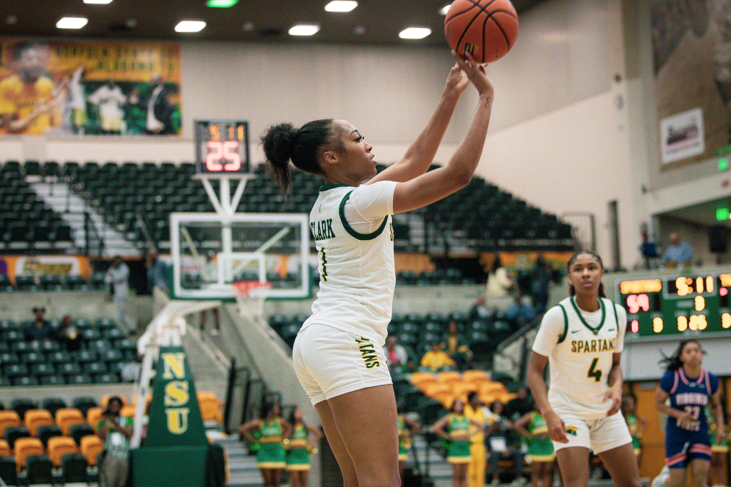 A player in a white uniform shoots a basketball during a game
