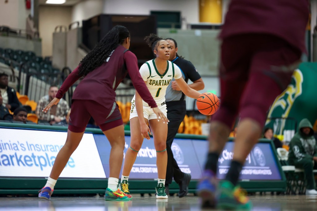 Da'Brya Clark searching for a player to pass the ball to while being guarded.