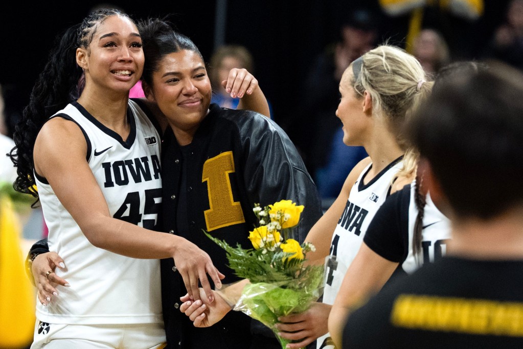 Iowa forward Hannah Stuelke (45) hugs Iowa forward Jada Gyamfi (23). Gyamfi is holding a bouquet of flowers.
