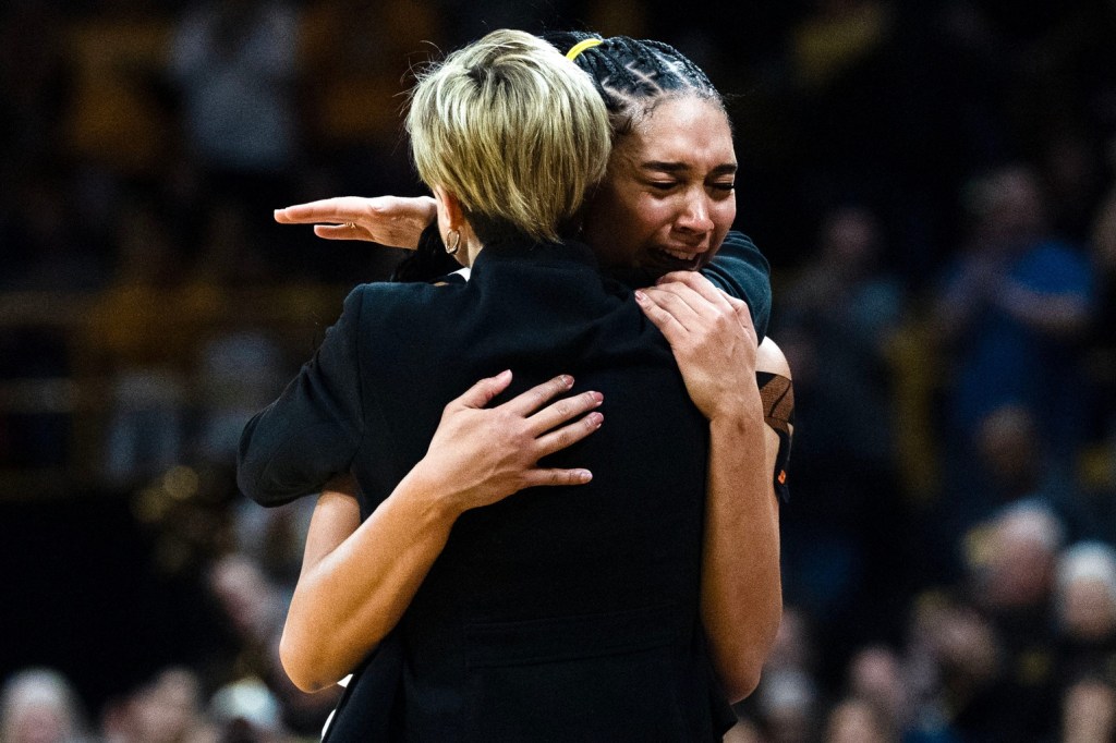 Iowa forward Hannah Stuelke (45) hugs Iowa head coach Jan Jensen as she comes off the court.