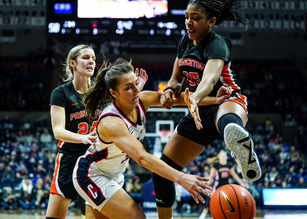 Princeton forward Chet Nweke jumps in the air, trying to deflect a pass from UConn guard Caroline Ducharme. Princeton guard Julia Cunningham also applies pressure on Ducharme from behind.