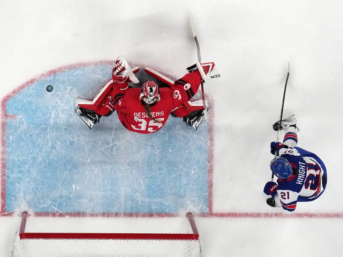 Ann-Renee Desbiens makes a save for Canada. Hilary Knight stands behind her.