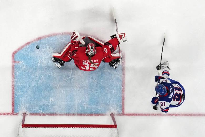 Ann-Renee Desbiens makes a save for Canada. Hilary Knight stands behind her.