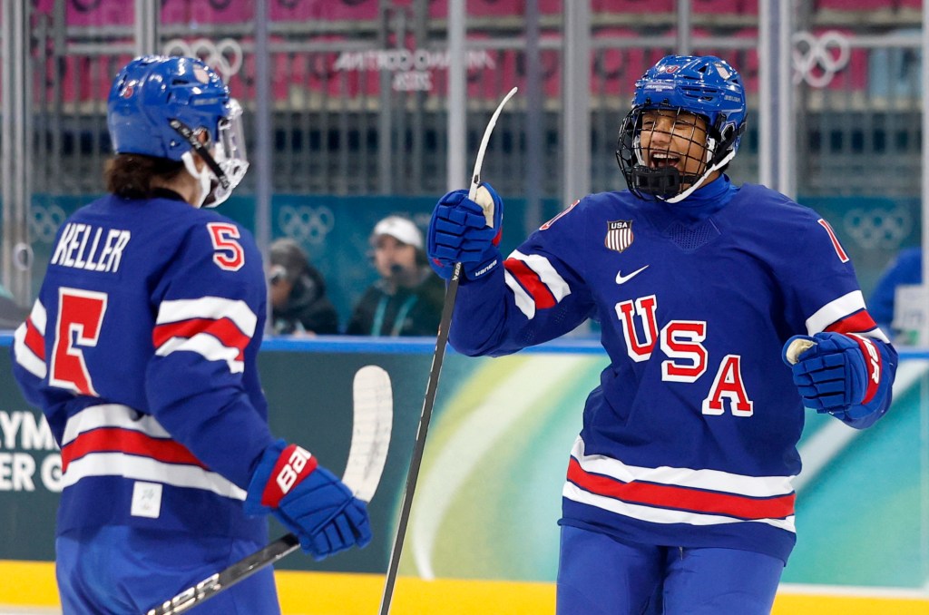 Edwards and Keller smile and celebrate a goal against Italy. They are both wearing blue home uniforms.