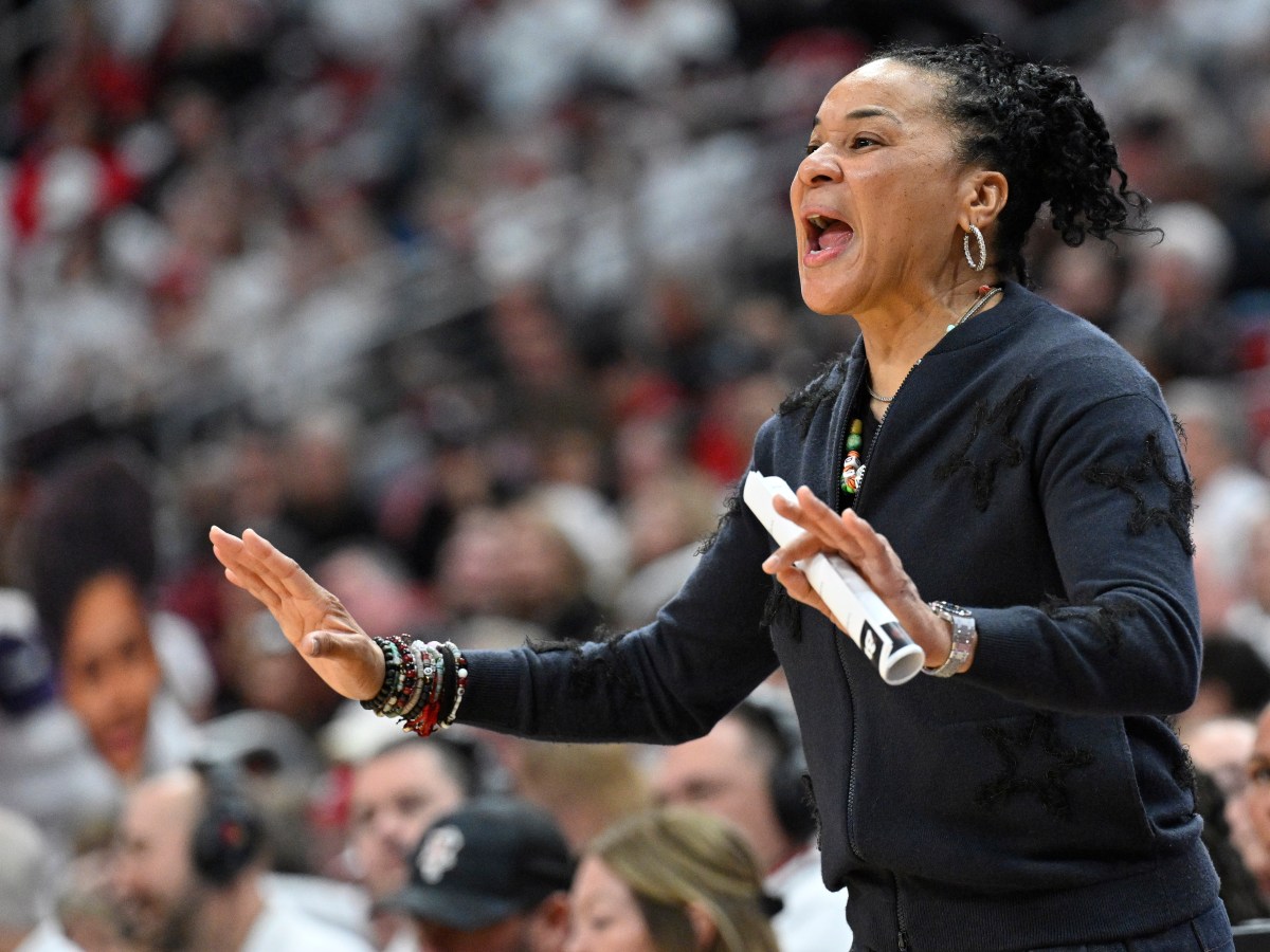 Dawn Staley coaching shouts directions from the sideline while clutching rolled up paper in her hand