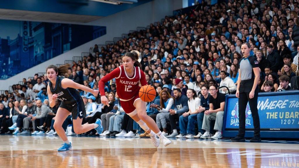 Harvard guard Karlee White dribbles the ball with her left hand just inside the 3-point line. A Columbia defender is behind her and to her right, trying to get back in the play.