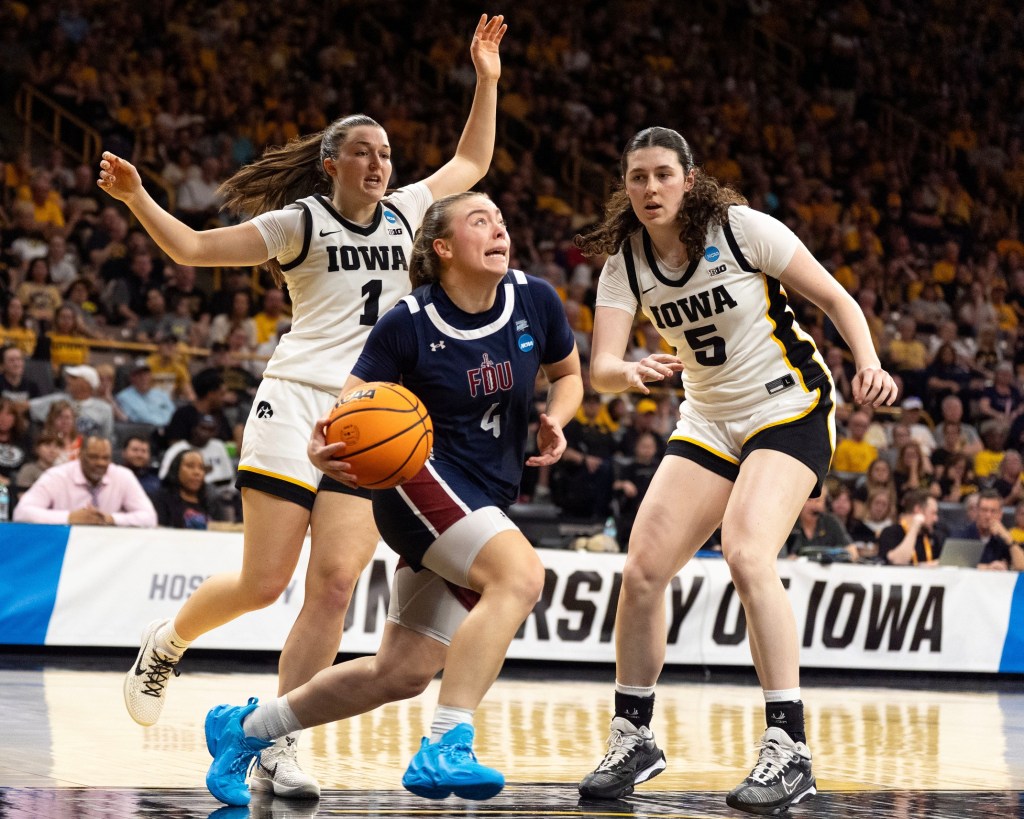 FDU guard Ava Renninger drives toward the basket between as Iowa guard Taylor Stremlow and Iowa center Ava Heiden during a First Round 2026 NCAA Tournament game at Carver-Hawkeye Arena in Iowa City, Iowa,.