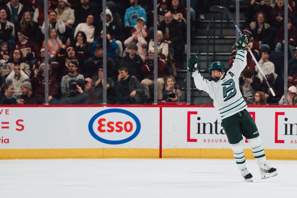 Müller smiles and raises her arms and celebration as she looks at the goal scorer out of frame. She is wearing a white away uniform.