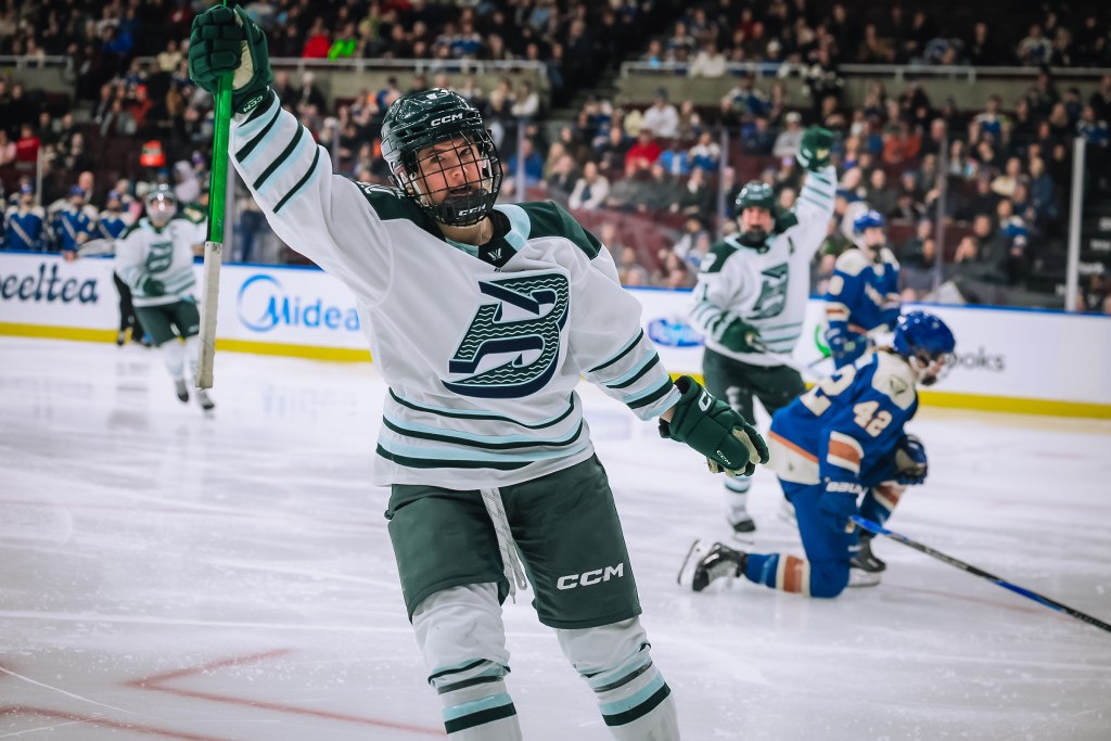 Winn raises her arm in celebration after scoring. She is wearing a white away uniform.