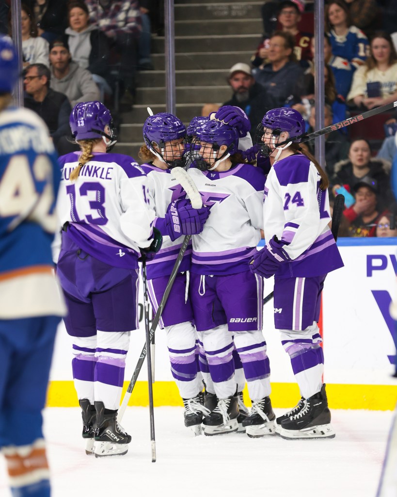 The Frost celebrate with smiles and a group hug. They are wearing white away uniforms.