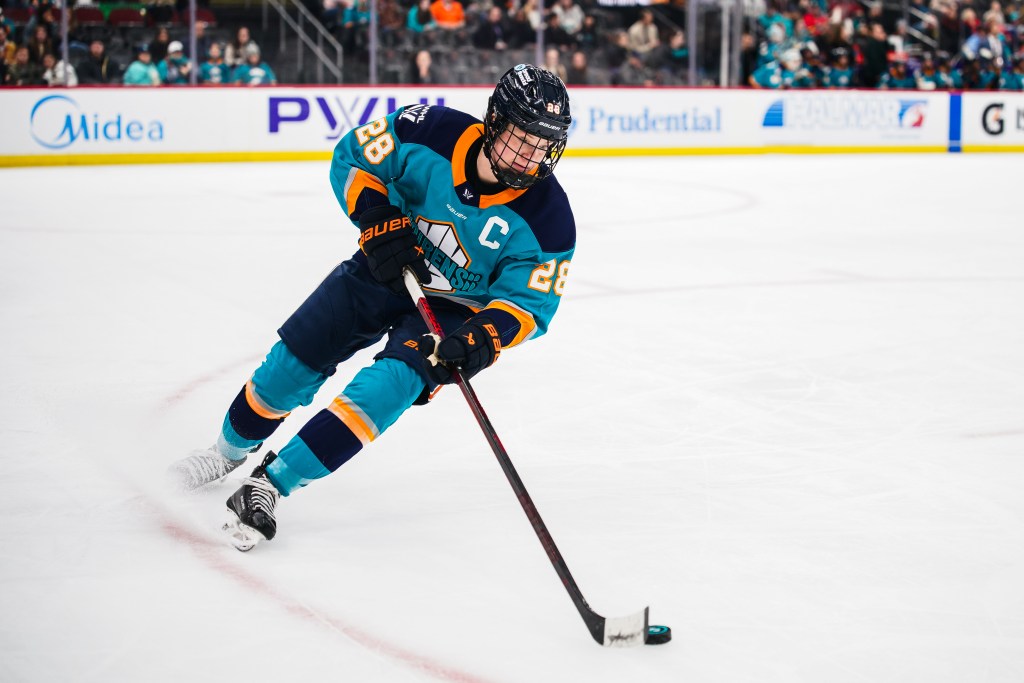 Zandee-Hart looks down at the puck as she skates. She is wearing a teal home uniform.