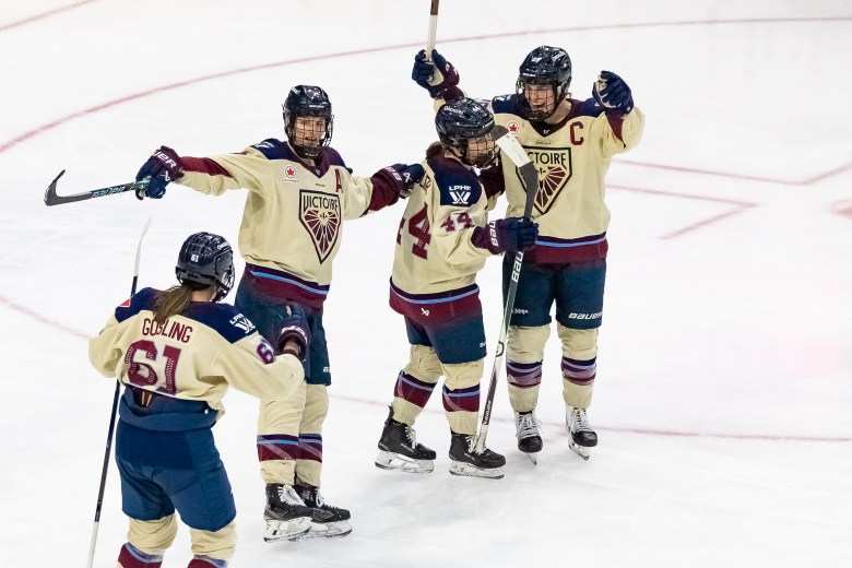 Four Victoire skaters celebrate with smiles and a group hug. They are wearing cream away uniforms.