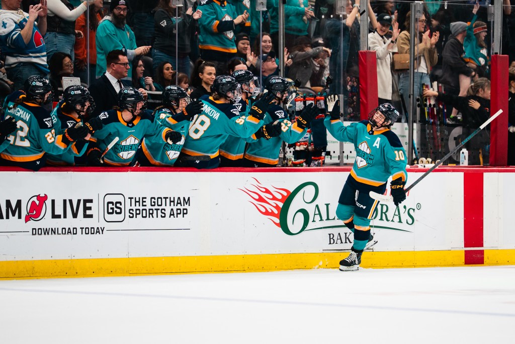 Fillier skates down the celebratory handshake line at the bench. The Sirens are all wearing teal home uniforms.