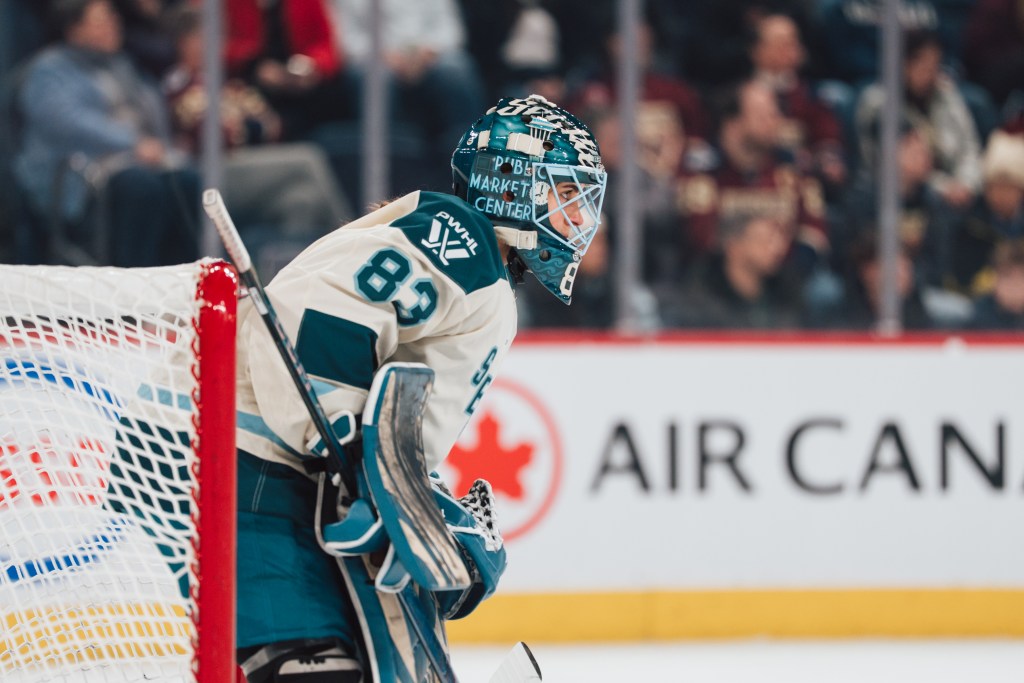 Murphy leans over as she looks up ice. She is wearing a cream away uniform.