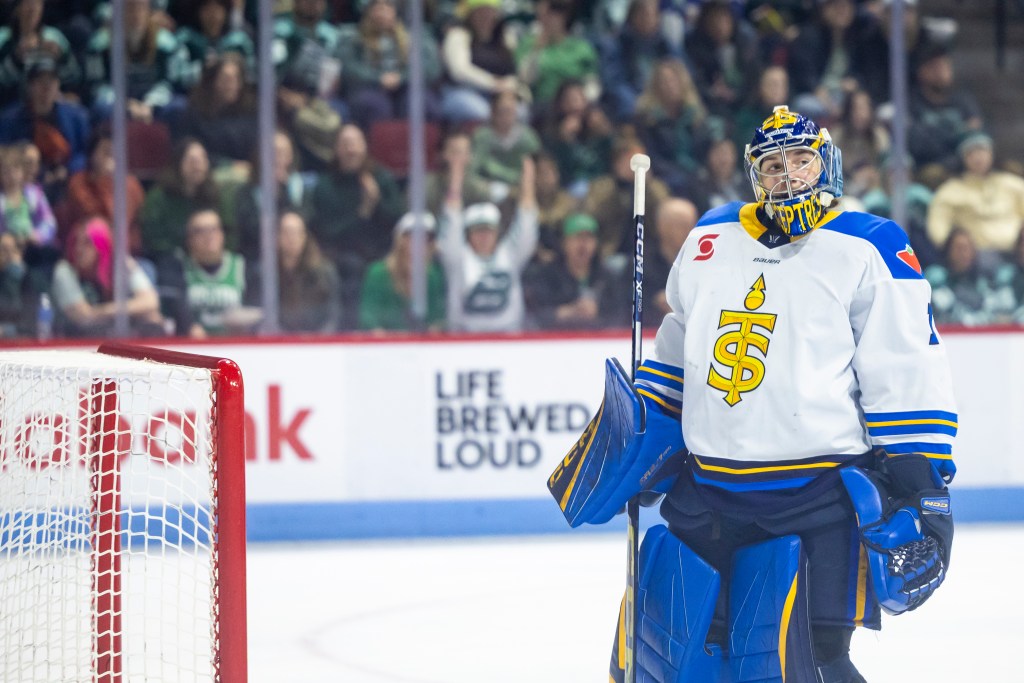 Kirk looks to her left as she stands facing her net. She is wearing a white away uniform.