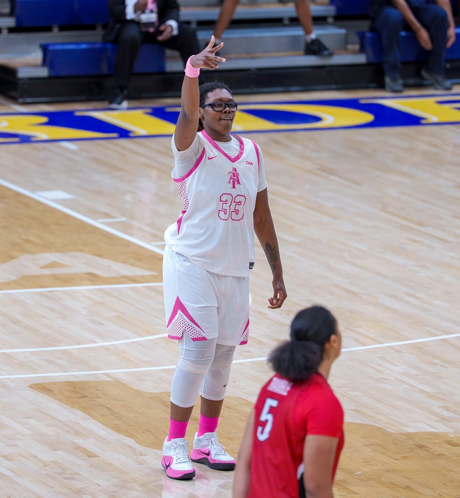 Chaniya Clark poses after making a 3-pointer with 3 fingers extended in celebration.