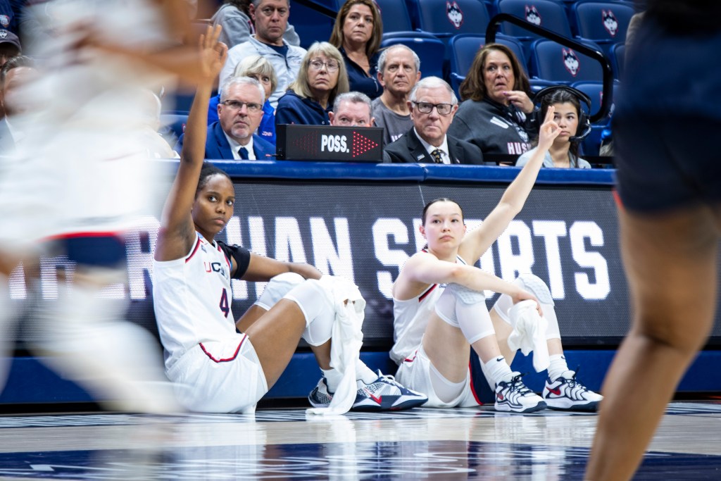 Blanca Quiรฑonez (L) and Kayleigh Heckel (R) signal the 3-point sign while seated in front of the scorer's table