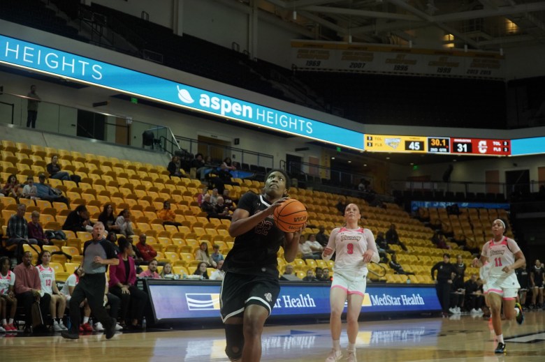 Grace Ezebilo races in for a basket while two Towson defenders trail behind her.