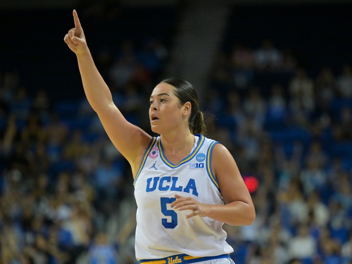 UCLA Bruins guard Charlisse Leger-Walker raises a finger in the air after a UCLA made shot. The Bruins’ home crowd is blurred in the background.