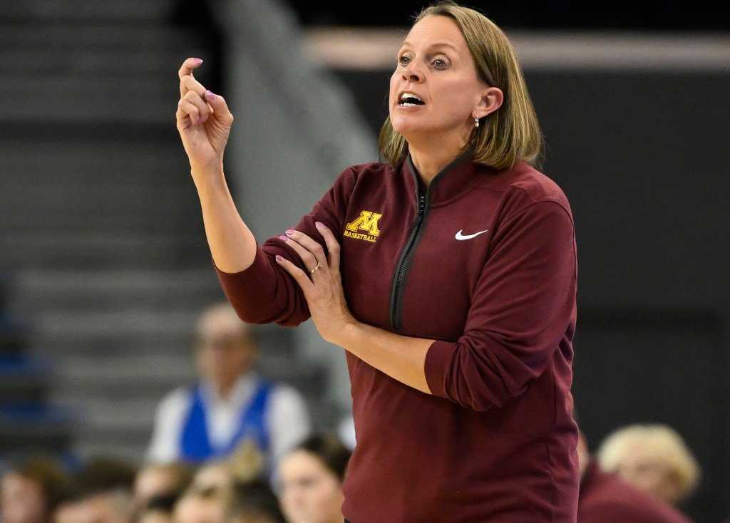 Minnesota coach Dawn Plitzuweit signals a play to her team during a 2025 game against UCLA. The Minnesota bench is blurred in the background
