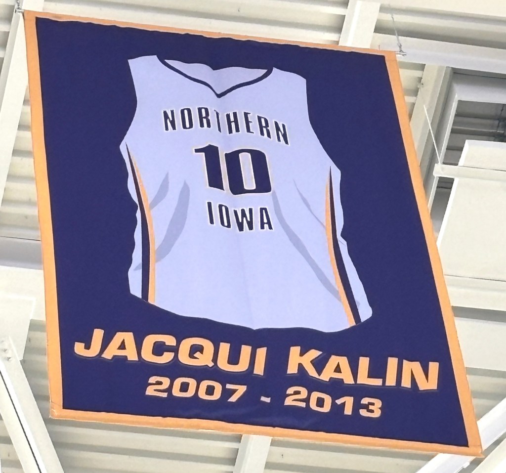 A banner showing point guard Jacqui Kalin's white No 10 Northern Iowa jersey with her name and 20027-2013 printed now hangs in the rafters at the McCleod Center in Cedar Falls, Iowa, as Kalin was the first University of Northern Iowa women's basketball player to have her jersey retired on Feb. 28, 2026.
