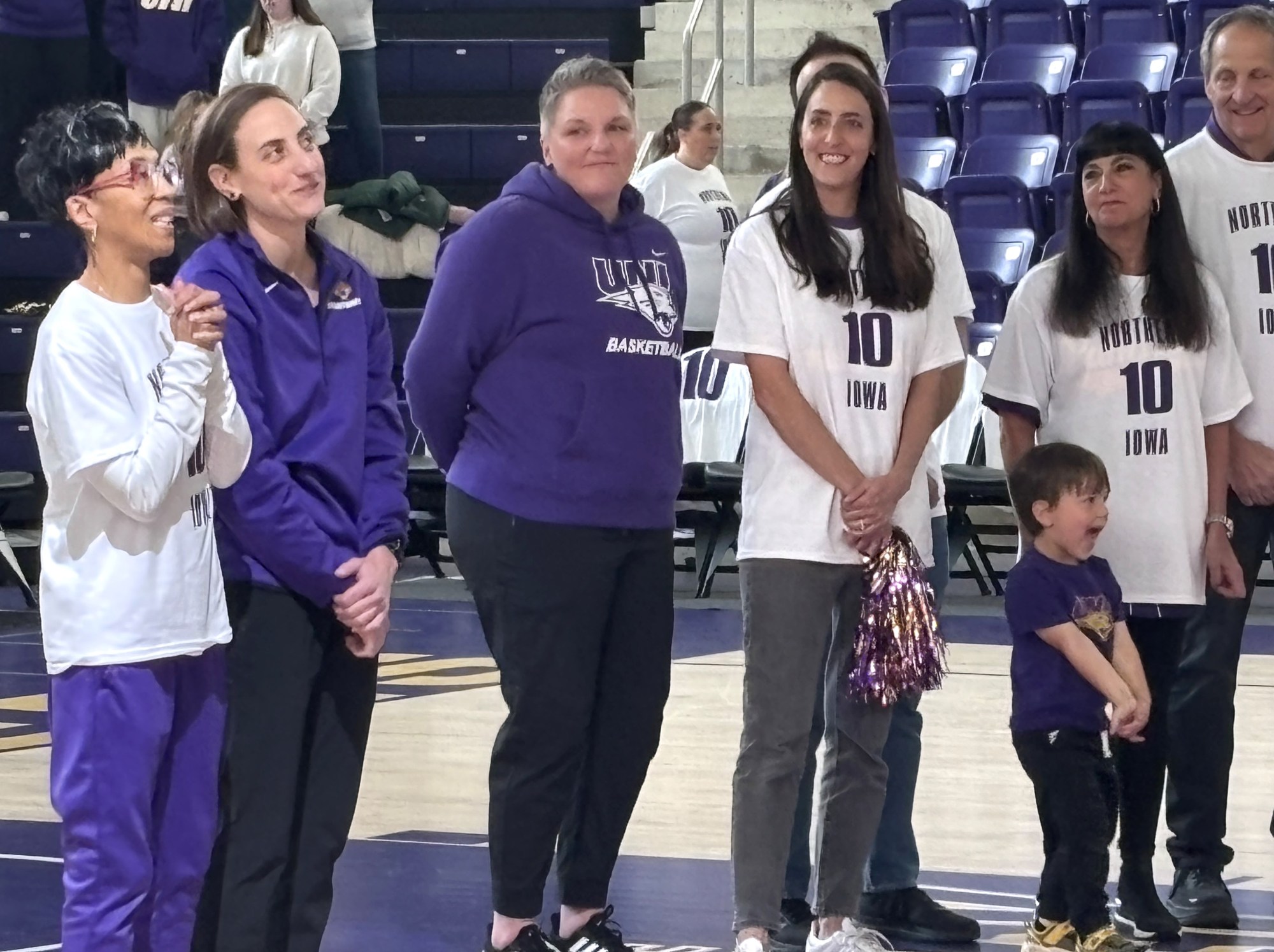 Former University of Northern Iowa point guard Jacqui Kalin her wife, Sarah Kalin, UNI head coach Tanya Warren, and her family watch a video as UNI women's basketball retired her #10 jersey in a ceremony at the McCloud Center in Cedar Falls, Iowa, before the start of UNI's game against UIC on Feb. 28, 2026.