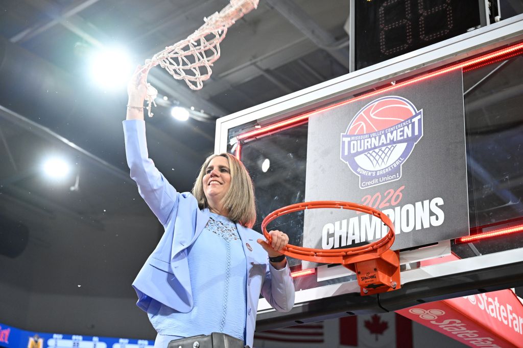 Murray State head coach Rechelle Turner swings the net in the air as she stands on the ladder at the hoop after the Racers won their second straight MVC Tournament championship.