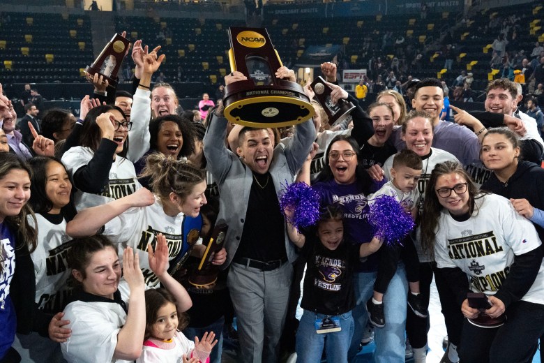 McKendree head coach Alexio Garcia and the women’s wrestling team celebrate with their First Place team trophy March 7, 2026 during the NCAA Women’s Wrestling Championship at Xtream Arena in Coralville, Iowa.